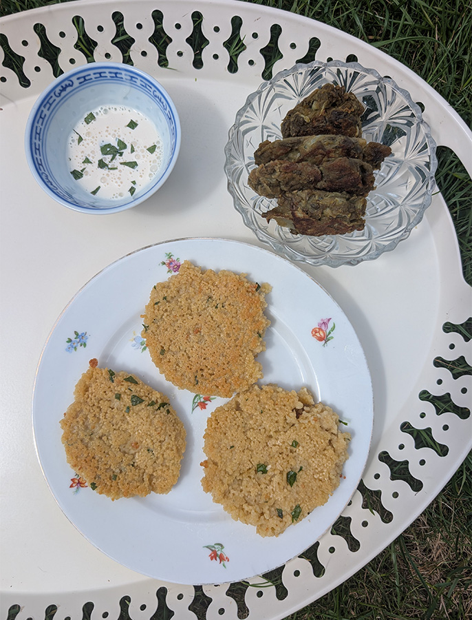 Assiette de batch cooking avec des galettes de semoule, des beignets de légumes maison et une sauce au yaourt aux herbes.