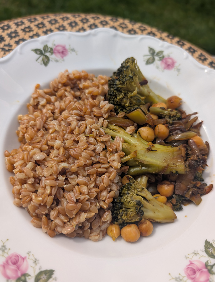 Assiette de blé complet accompagné de brocolis, pois chiches et légumes poêlés, préparée en batch cooking.